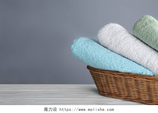 竹篮子中三块毛巾Fresh towels on wooden table, space for text